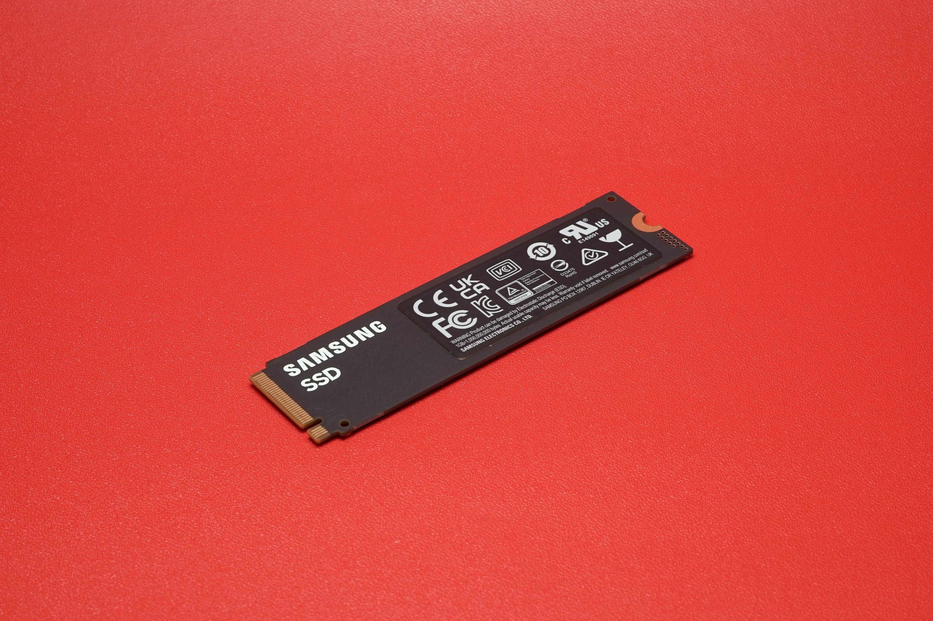 M.2 SSD drive on a red surface, showcasing its sleek design.